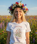 Leende kvinna med blomsterkrans bär en vit sommar-t-shirt med smultronmotiv