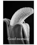 Närbild i svartvitt på en skalad banan med små vattendroppar mot en svart bakgrund och texten Good morning i vitt.