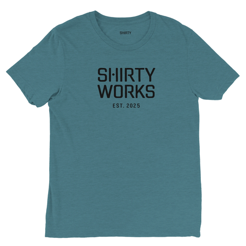 Shirty Works logga, EST. 2025, i svart på mörk turkos triblend t-shirt.