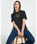 Sittande modell bär en t-shirt med stämningsfull grafisk illustration