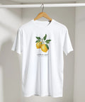 Realistiskt tryck av två gula citroner med gröna blad och texten "Lemon Zest" på vit t-shirt.