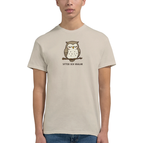Tecknad sovande uggla på gren med text "SITTER OCH UGGLAR" på beige t-shirt.