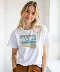 Kvinna bär vit t-shirt med nostalgisk grafisk havsmålning
