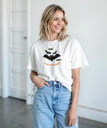 Svarta fladdermöss med orange ögon och texten "Glad Halloween" på vit t-shirt.