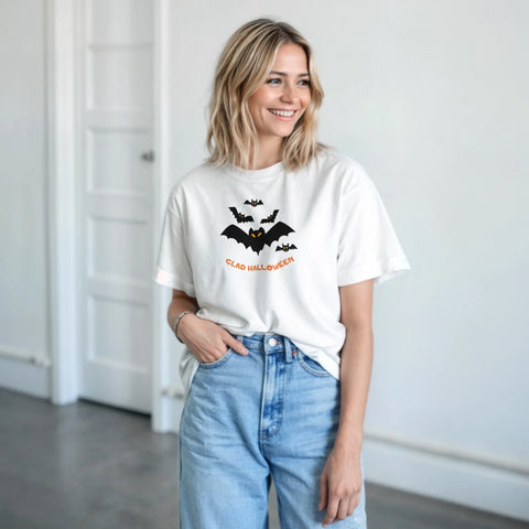 Svarta fladdermöss med orange ögon och texten "Glad Halloween" på vit t-shirt.