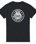 Svart t-shirt med vitt cirkulärt emblem föreställande en hamburgare och texten Det blir la gött