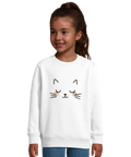 Barn i vit sweatshirt med grafiskt kattansikte och rosa kinder