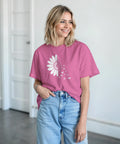 Vit tusensköna som övergår i fjärilar på rosa t-shirt.