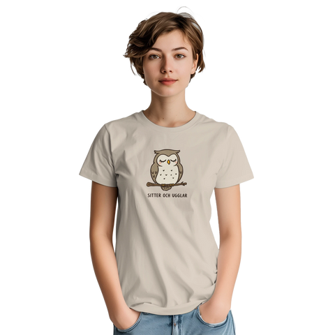 Tecknad uggla med slutna ögon på gren, text "SITTER OCH UGGLAR" på beige t-shirt.