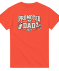 Orange t-shirt med texten Promoted to Dad 2027, nappflaska och napp.