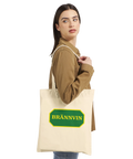 Kvinna som bär en beige tygkasse med humoristiskt brännvinstryck