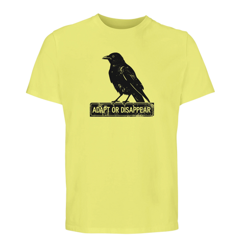 Svart korp med sliten text "ADAPT OR DISAPPEAR" på skylt, tryckt på en ljusgul ekologisk T-shirt.