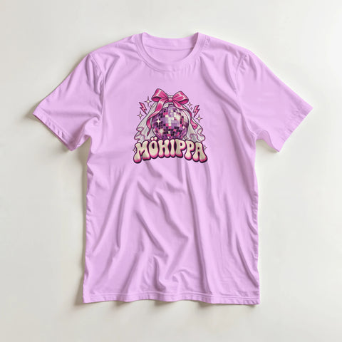 Lila t-shirt med texten ”Möhippa”, discokula, rosa rosett och brudslöja, lagd på en ljus bakgrund.