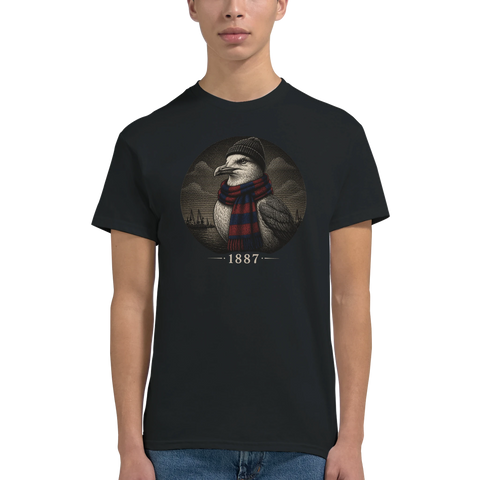 Man bär en svart t-shirt med ett cirkulärt porträtt av en mås och årtalet 1887