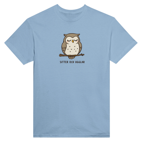 Tecknad brun uggla med slutna ögon på gren, text "SITTER OCH UGGLAR" på ljusblå t-shirt.
