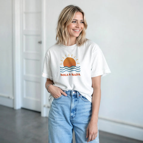 Retro "Sola & Bada" tryck med orange sol och blå vågor på vit t-shirt.