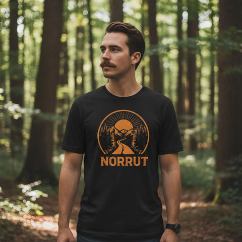 Man med mustasch bär en t-shirt med naturmotiv i en lummig skogsmiljö