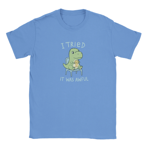 Tecknad dinosaurie med "Meh"-medalj och texten "I tried. It was awful" på ljusblå t-shirt.