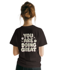 Vintage inspirerat ryggtryck med peppande citat på brun t-shirt
