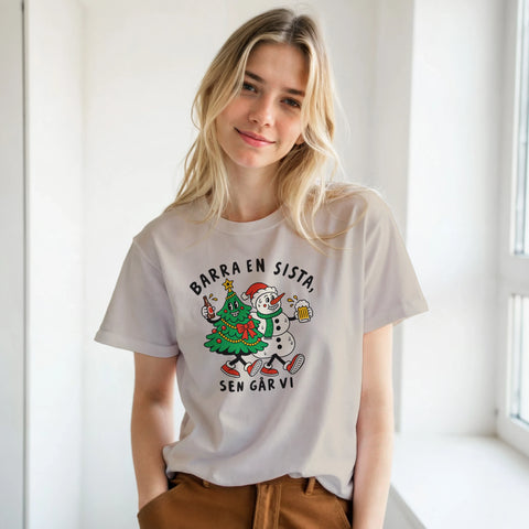 Modell i beige t-shirt med en julgran och snögubbe som skålar och texten ”Barra en sista, sen går vi”.
