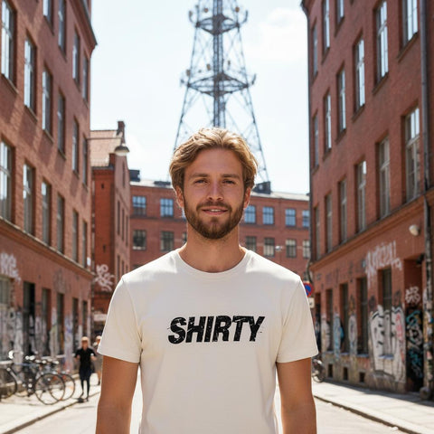 Svart, snedställd "SHIRTY" logotyp med distressed-effekt på en krämvit premium herr-t-shirt.
