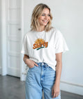 Orange Shirty-logga med soluppgång över apelsinskiva på vit t-shirt.
