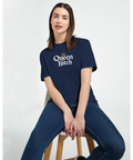 Sittande kvinna i marinblå t-shirt med statement-design och krona