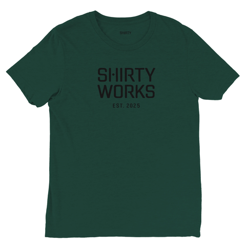 Mörkgrön T-shirt med texten "SHIRTY WORKS EST. 2025" i mörkare gråsvart, minimalistisk stil.