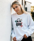 Kvinna bär vit sweatshirt med grafiskt porträtt och texten Hon log men inte mot dig