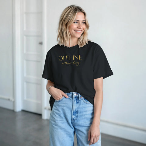 Kvinna bär en svart t-shirt med guldtext och avslappnad stil