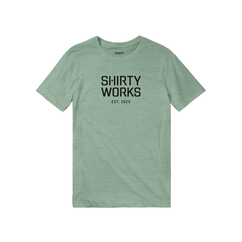 Shirty Works EST. 2025 logga på en grön triblend t-shirt.