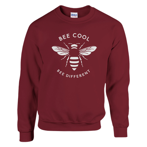 Vitt stiliserat bi med texten "BEE COOL BEE DIFFERENT" på mörkvinröd sweatshirt.