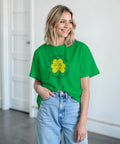 Kvinna bär en grön t-shirt med en glad gul fyrklöver och irländsk text