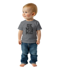Ge mig mat" text på grå baby t-shirt med svart tryck, bärs av ett leende blont barn.