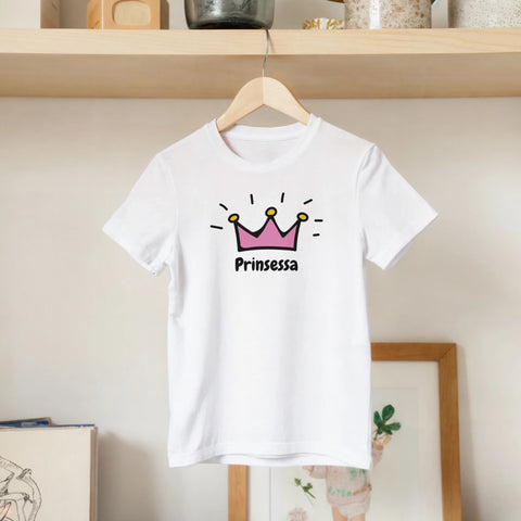 Rosa krona med guldtoppar och text "Prinsessa" i svart, på vit barntröja.