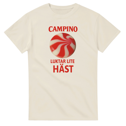 Ljus t-shirt med röd-vit karamell och röd text “Campino – Luktar lite häst”, humoristiskt retro godismotiv.
