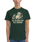 Man bär mörkgrön t-shirt med roligt julmotiv av en skålande tomte