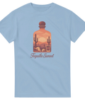 Tequila Sunset-motiv med ökenlandskap, kaktusar, solnedgång, dödskallar, shotglas på ljusblå t-shirt.