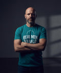 Skallig man med skägg bär turkos t-shirt med kaxig text