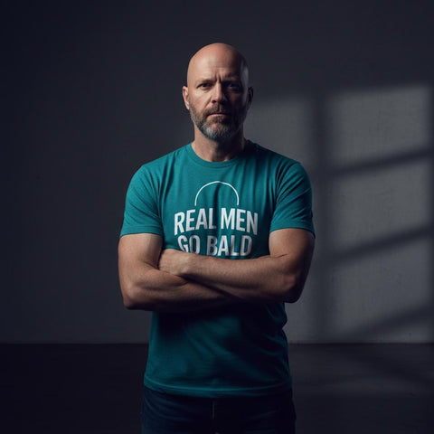 Skallig man med skägg bär turkos t-shirt med kaxig text