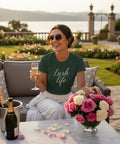 Kvinna i grön t-shirt skålar med champagne i lyxig trädgård