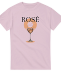 Rosévin i glas med is framför solnedgång, text "ROSÉ", på ljusrosa t-shirt.