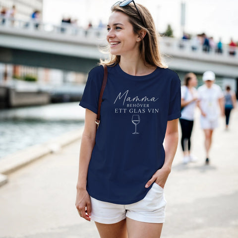 Kvinna bär en marinblå t-shirt med texten Mamma behöver ett glas vin