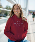 Leende kvinna i röd hoodie med vit ”For Helvede Copenhagen”-design.