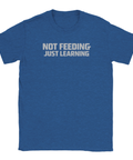 NOT FEEDING JUST LEARNING" text på en mörkblå t-shirt med rund hals.
