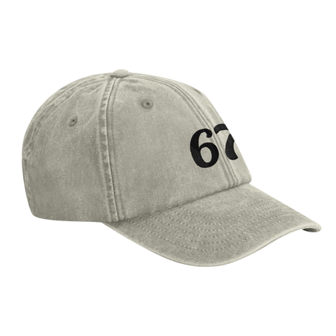 Siffran "67" i svart på en gråmelerad, sliten dad cap.