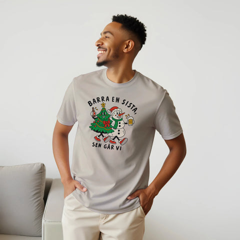 Modell i beige t-shirt med en julgran och snögubbe som skålar och texten ”Barra en sista, sen går vi”.