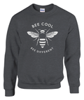 Minimalistisk vit bi-design med text "BEE COOL BEE DIFFERENT" på mörkgrå sweatshirt.