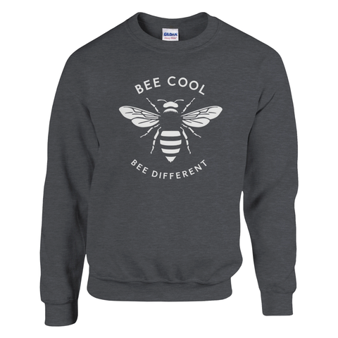 Minimalistisk vit bi-design med text "BEE COOL BEE DIFFERENT" på mörkgrå sweatshirt.