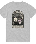 Grå t-shirt med tecknad gravsten och två personer, en ledsen och en glad, med texten “Folk dör – och du lever vidare. Det känns orättvist.”
